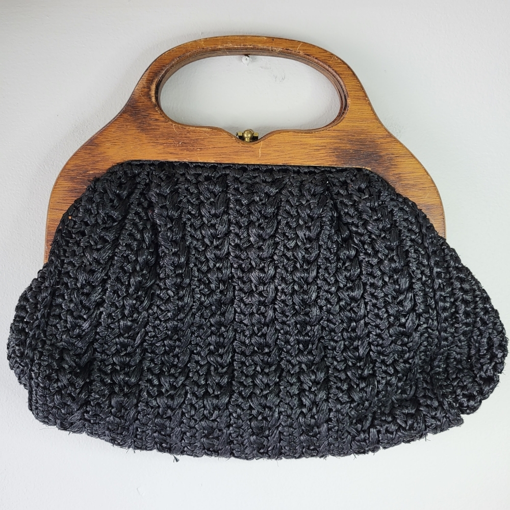 Woven black handbag with wooden handles and metal closure.